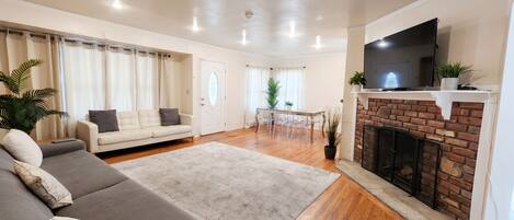 A living room with a sofa, a fireplace, a television, and a dining area.