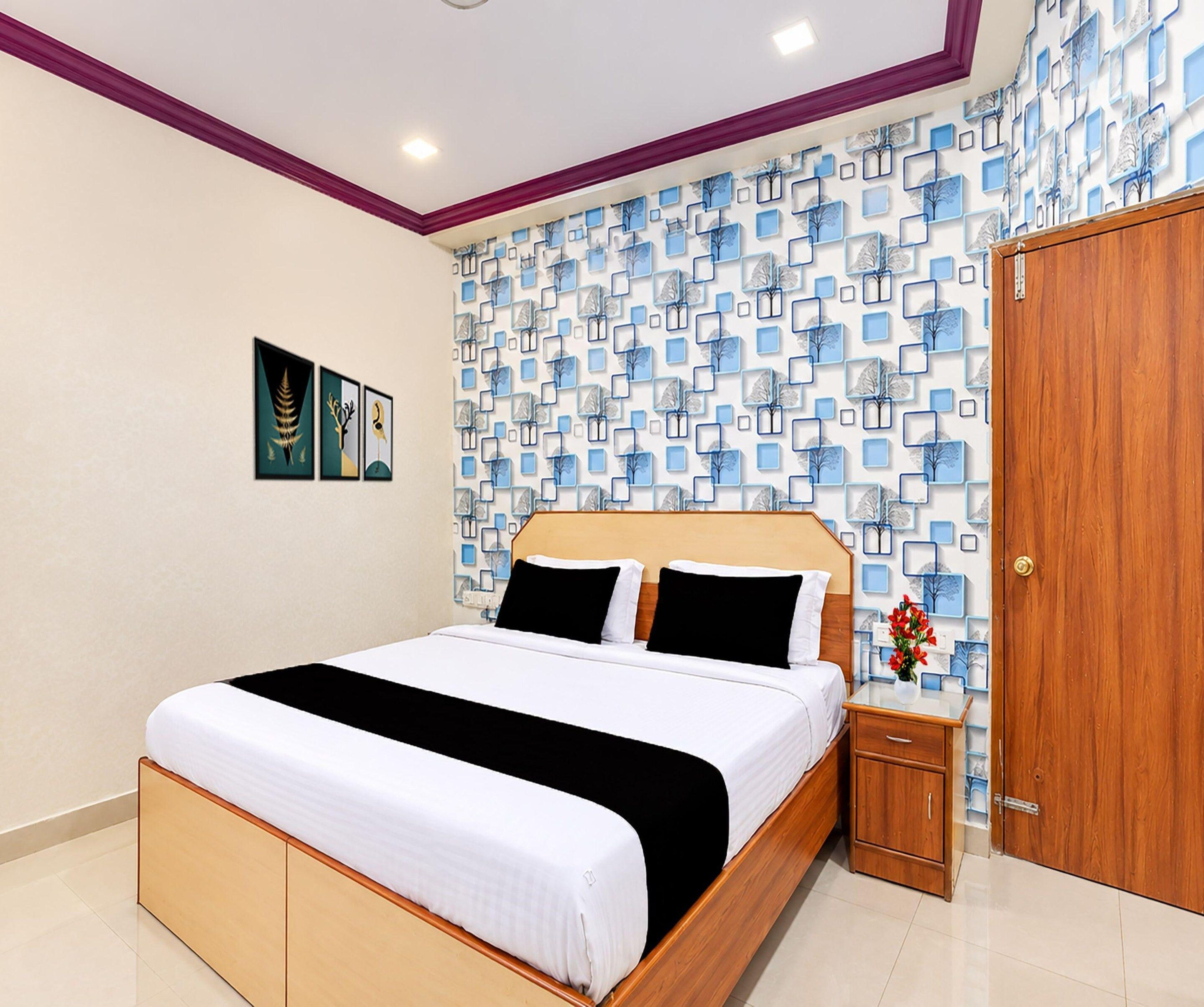 Une chambre à coucher comprenant un lit, une table de chevet, une armoire et un mur orné d’un motif géométrique.