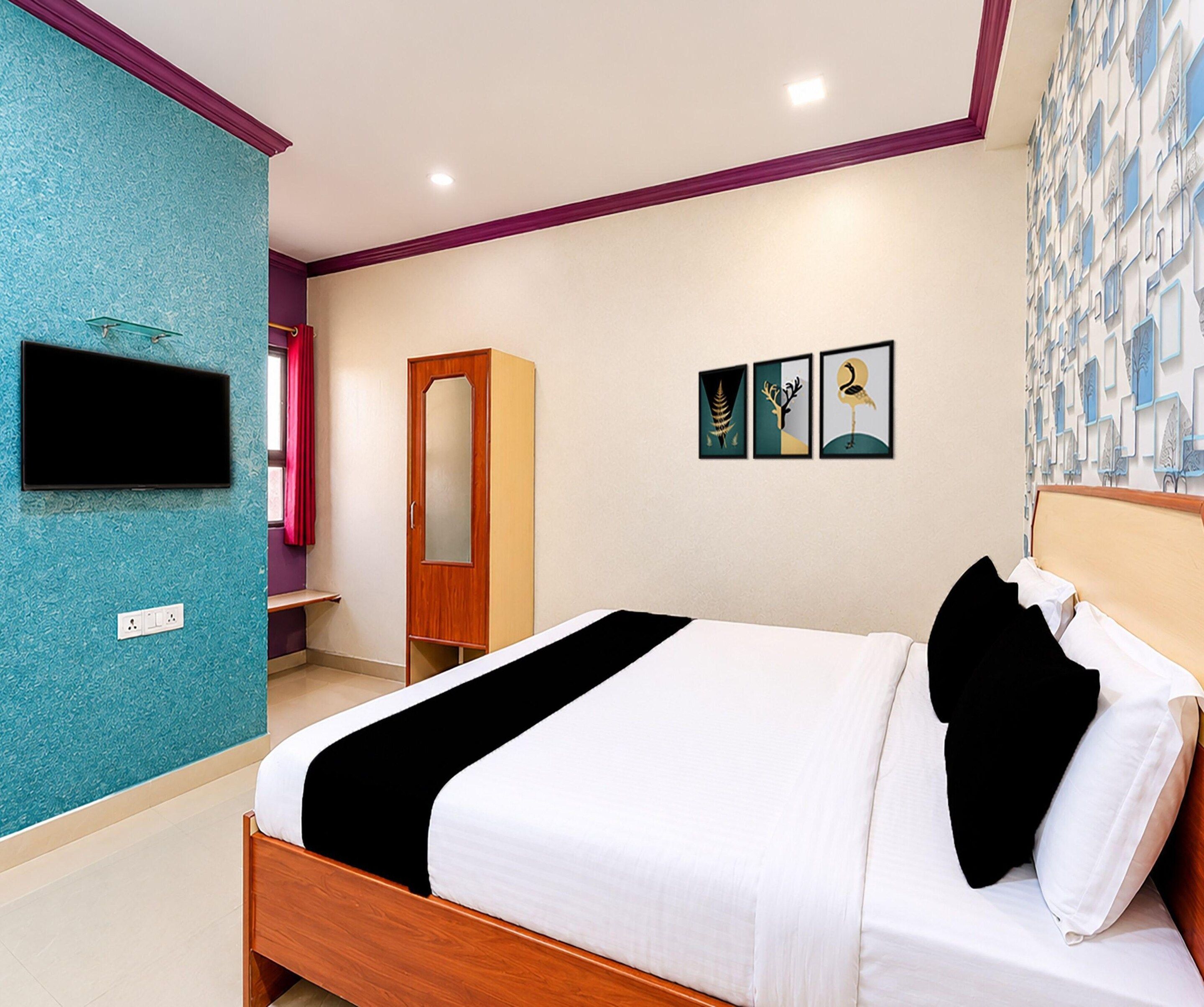 A hotel room with a bed, a wardrobe, a TV, and artwork on the wall.