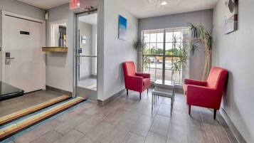 A reception area with a glass door entrance, a small table with chairs, and a view of the outdoors through large windows.