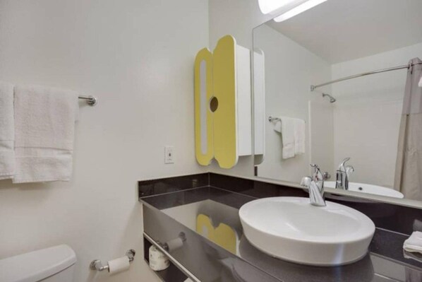 Une salle de bain moderne avec un lavabo blanc, un grand miroir et un porte-serviettes.