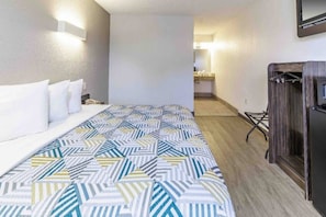 Quarto de hotel com cama, secretária e cadeira.