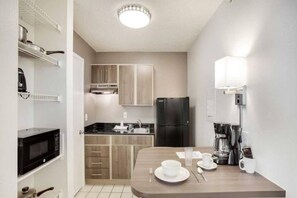 Una cocina compacta equipada con microondas, refrigerador y cafetera.