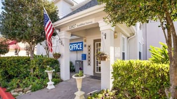 A building with a sign reading '1827 SouthWest Freeway OFFICE' and an American flag.