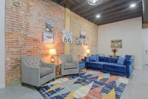 A room with a brick wall, two armchairs, a sofa, and a rug. - Galena Route 66 Retreat w/ Historic Brick Style (Galena)