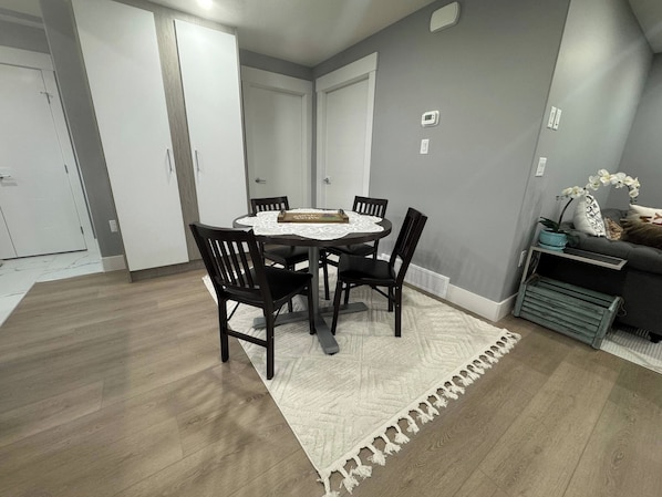 A dining area with a round table, four chairs, and a white table runner.