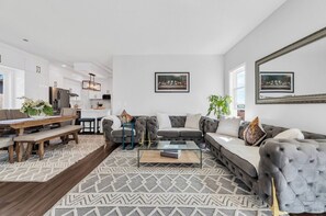 Ein modernes Wohnzimmer mit einer Couch, einem Couchtisch und einem Essbereich mit einer Bank.
