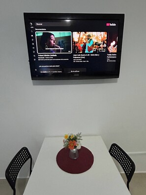 Un televisor de pantalla plana montado en la pared mostrando una interfaz de YouTube con sugerencias de videos.