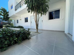Un edifici modern amb teulada plana, un balcó i una zona d'entrada enrajolada.