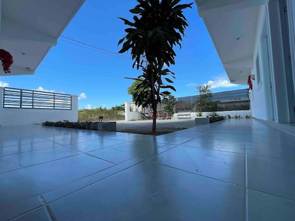 A spacious outdoor area with a tiled floor, a small tree, and a clear blue sky. - Blue Night Aparta Hotel Your haven of peace (Punta Cana)