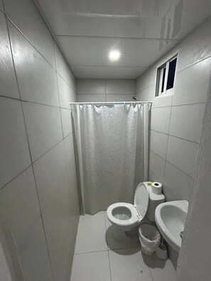Un baño pequeño con azulejos, un inodoro, un bidé y una cortina de ducha.