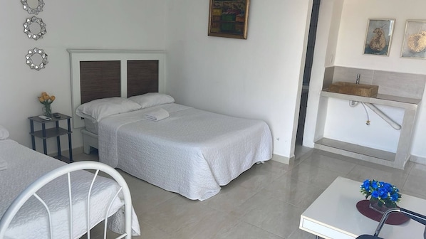 Un dormitorio con cama, mesita de noche y una pequeña mesa con un florero.