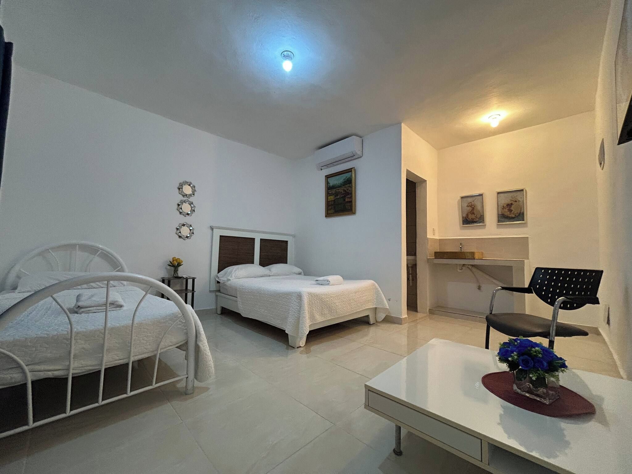Een hotelkamer met een bed, een bureau, een stoel en een tafeltje met een bloevas.