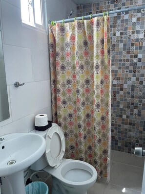 Un baño con inodoro, lavamanos y cortina de ducha estampada con flores.