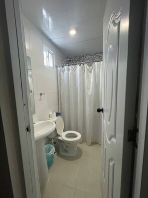 Un baño con inodoro, lavamanos y cortina de ducha.