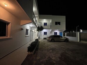 Un edificio de dos pisos con un automóvil estacionado en la entrada, de noche.