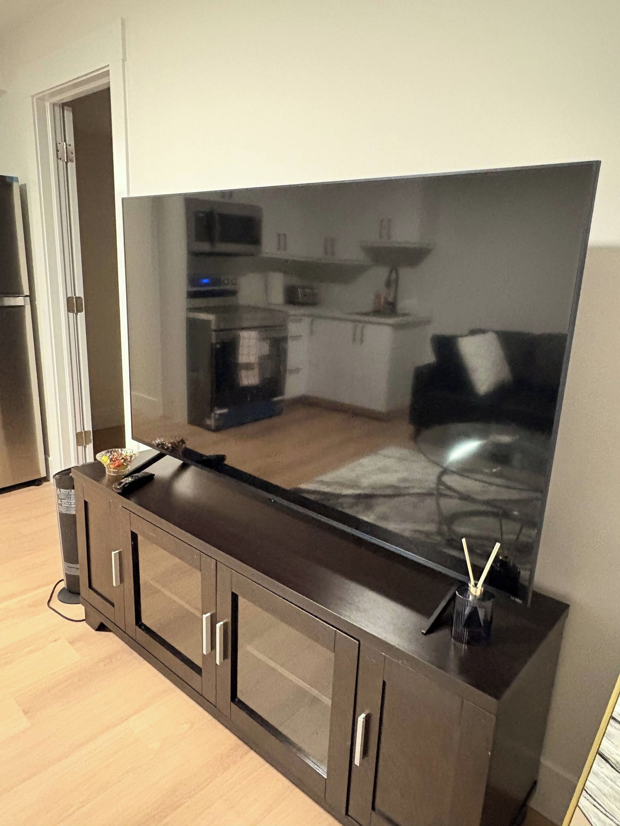 A modern kitchen with a large flat-screen TV mounted on a cabinet.