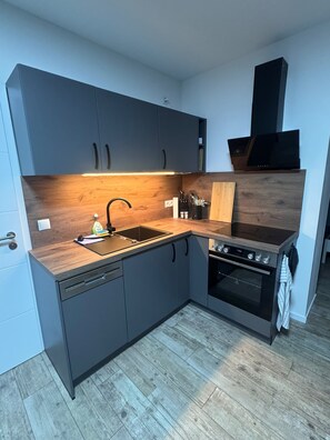 A modern kitchen with grey cabinets, a wooden countertop, a built-in oven, and a dishwasher. - New Listing (Huy)