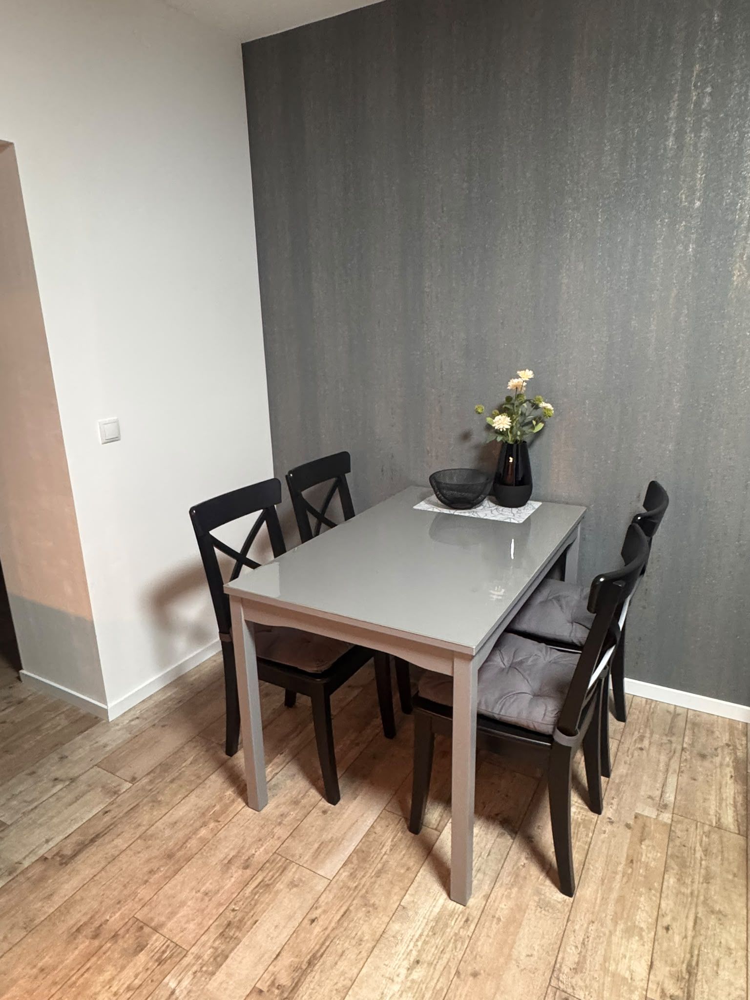 A dining area with a table, chairs, and a vase with flowers.