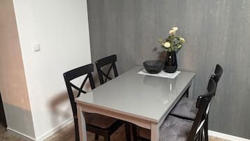 A dining area with a table, chairs, and a vase with flowers.