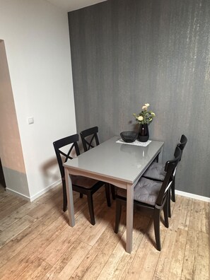 A dining area with a table, chairs, and a vase with flowers. - New Listing (Huy)