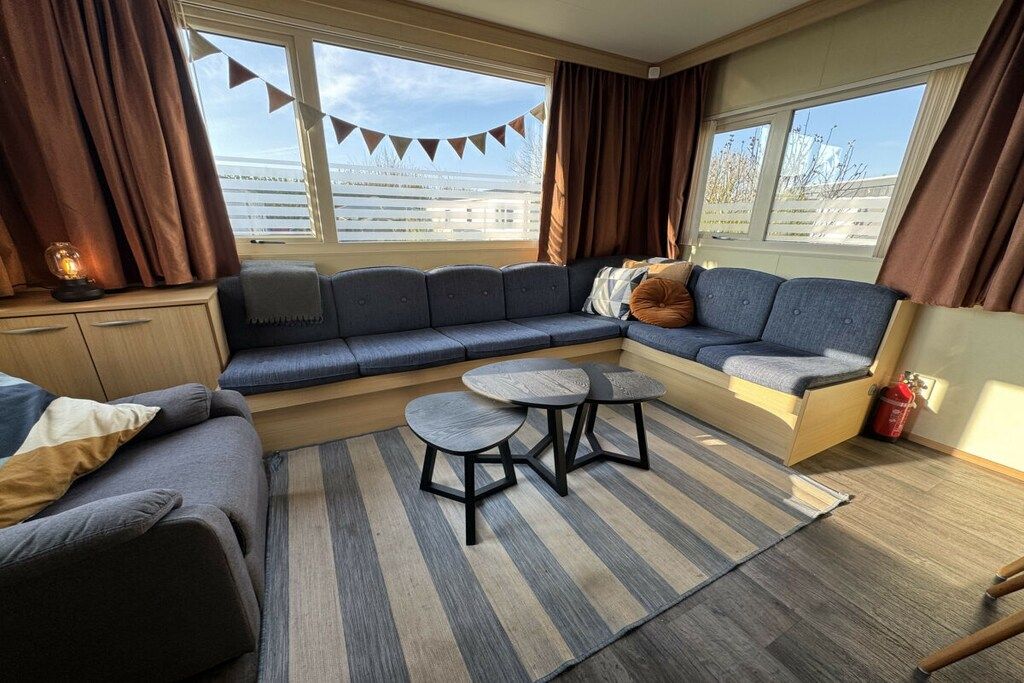 A cozy room with a sectional sofa, a small dining table, and a view of the outdoors.