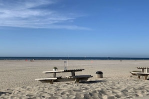 A beach with picnic tables and a trash can.
