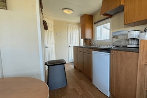 A compact kitchen with wooden cabinets, a dishwasher, and a coffee maker.