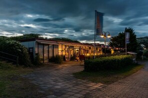 A building with a glass facade, a flag, and a paved entrance.