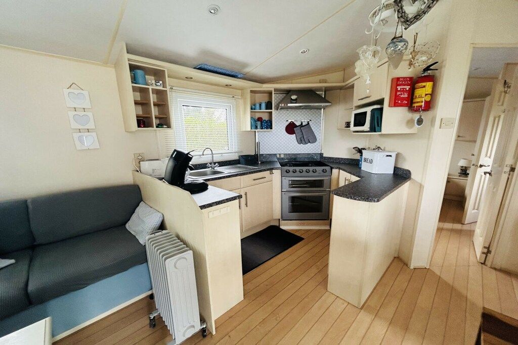 A compact kitchen with a sink, stove, and microwave, a small dining area, and a sofa.
