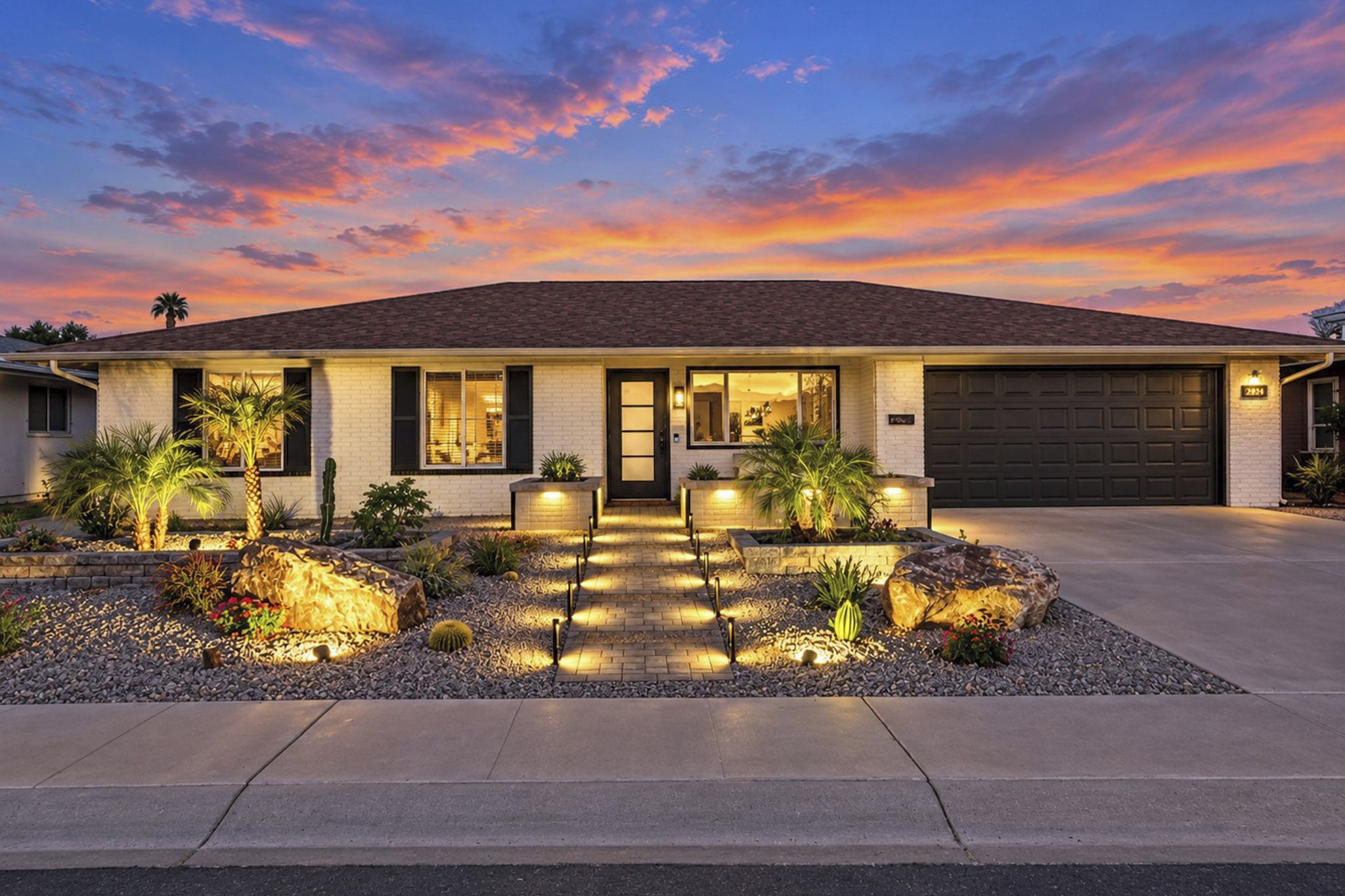A single-story house with a garage, a front porch with a bench, and a well-lit entrance.