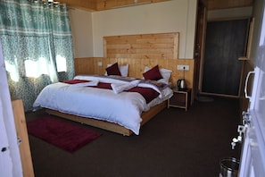 A wooden bed with a headboard, a bedside table with a kettle, and a red rug. - Snow Lotus Kalpa (Jangal Mehfuza Mehduda C-)