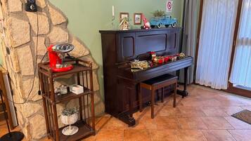 Un salon chaleureux avec un mur en pierre, une table basse en bois sur laquelle se trouve un appareil électroménager rouge, un piano en bois foncé et un camion jouet bleu posé sur le dessus.