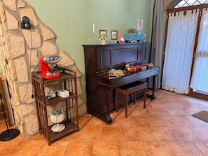 A cozy living room with a stone wall, a wooden coffee table with a red appliance, a dark wooden piano, and a blue toy truck on top. - New Listing (S. Polo dei Cavalieri)