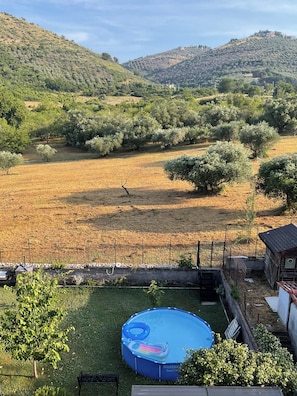 A backyard with a blue inflatable pool, a fenced area, and a view of a hilly landscape. - New Listing (S. Polo dei Cavalieri)