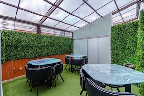 An indoor space with a glass ceiling, green foliage walls, and tables with chairs. - Ayenda CGH Bogota Airport (Bogotá)