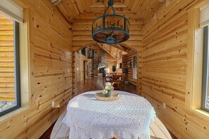 A wooden interior with a spiral staircase, a round table with a lace tablecloth, and a chandelier.