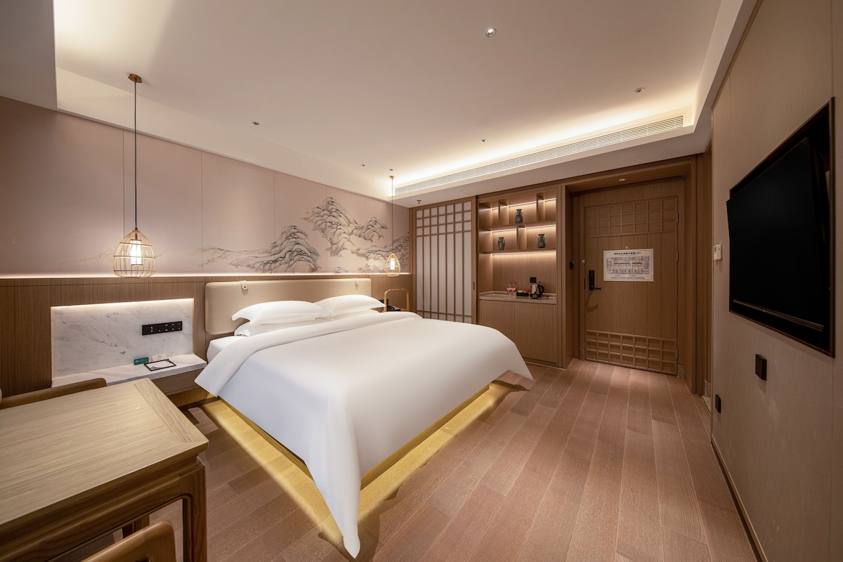 Een moderne hotelkamer met een groot bed, nachtkastjes, een bureau en een televisie.