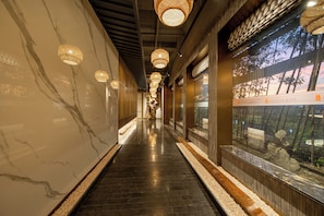 A corridor with a marble wall, wooden flooring, and hanging lamps. - QI YUE Song yin Hotel (Hangzhou)