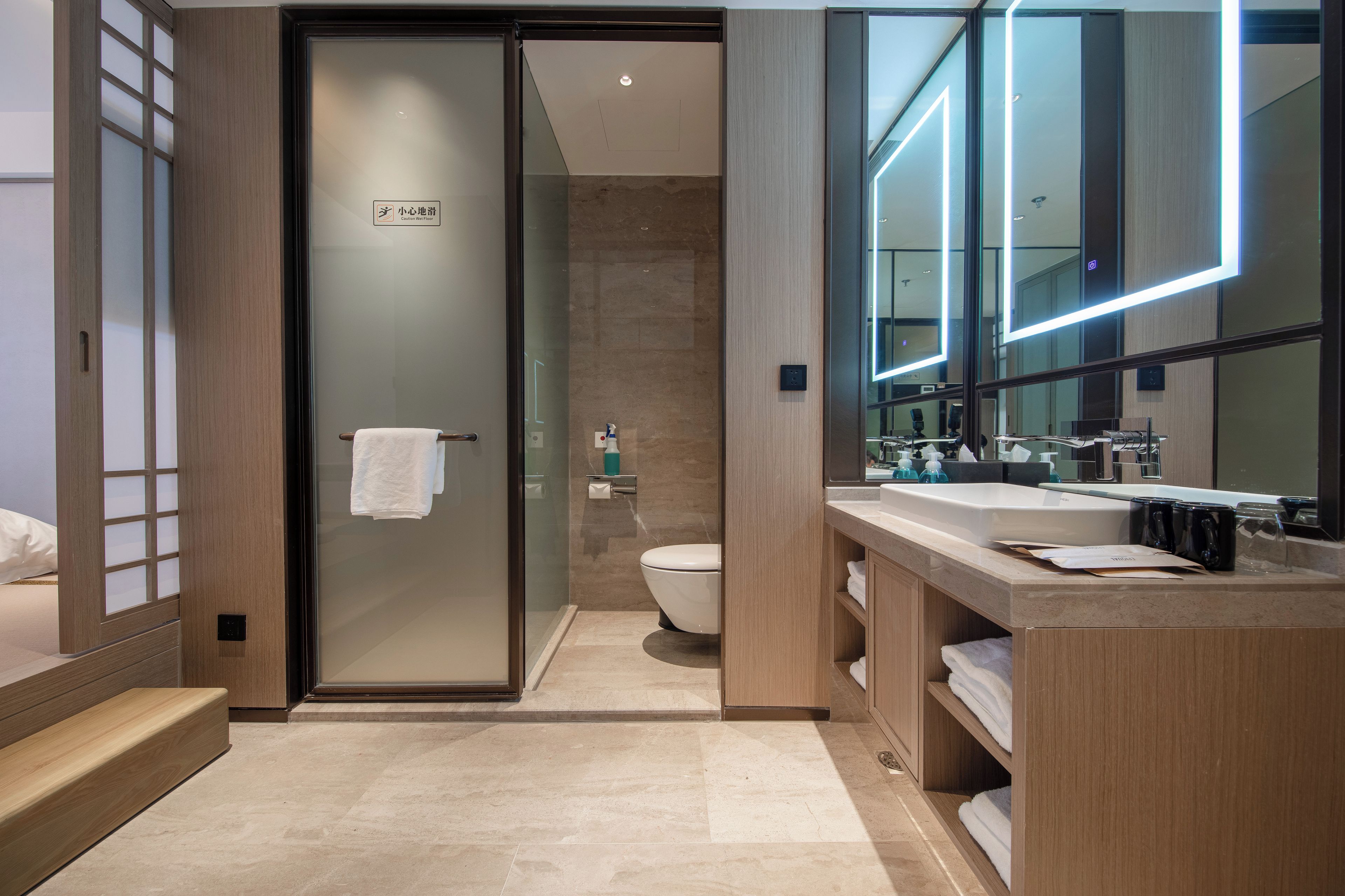 Ein modernes Badezimmer mit Duschkabine aus Glas, Toilette, Waschbecken mit Spiegel und Handtuchhalter.