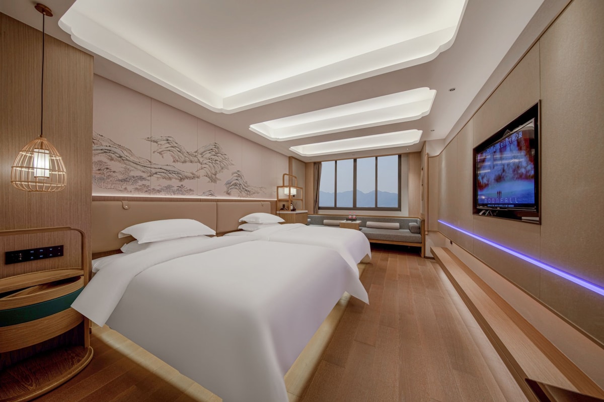 Een hotelkamer met een groot bed, een televisie, een bureau en een kunstwerk aan de muur.