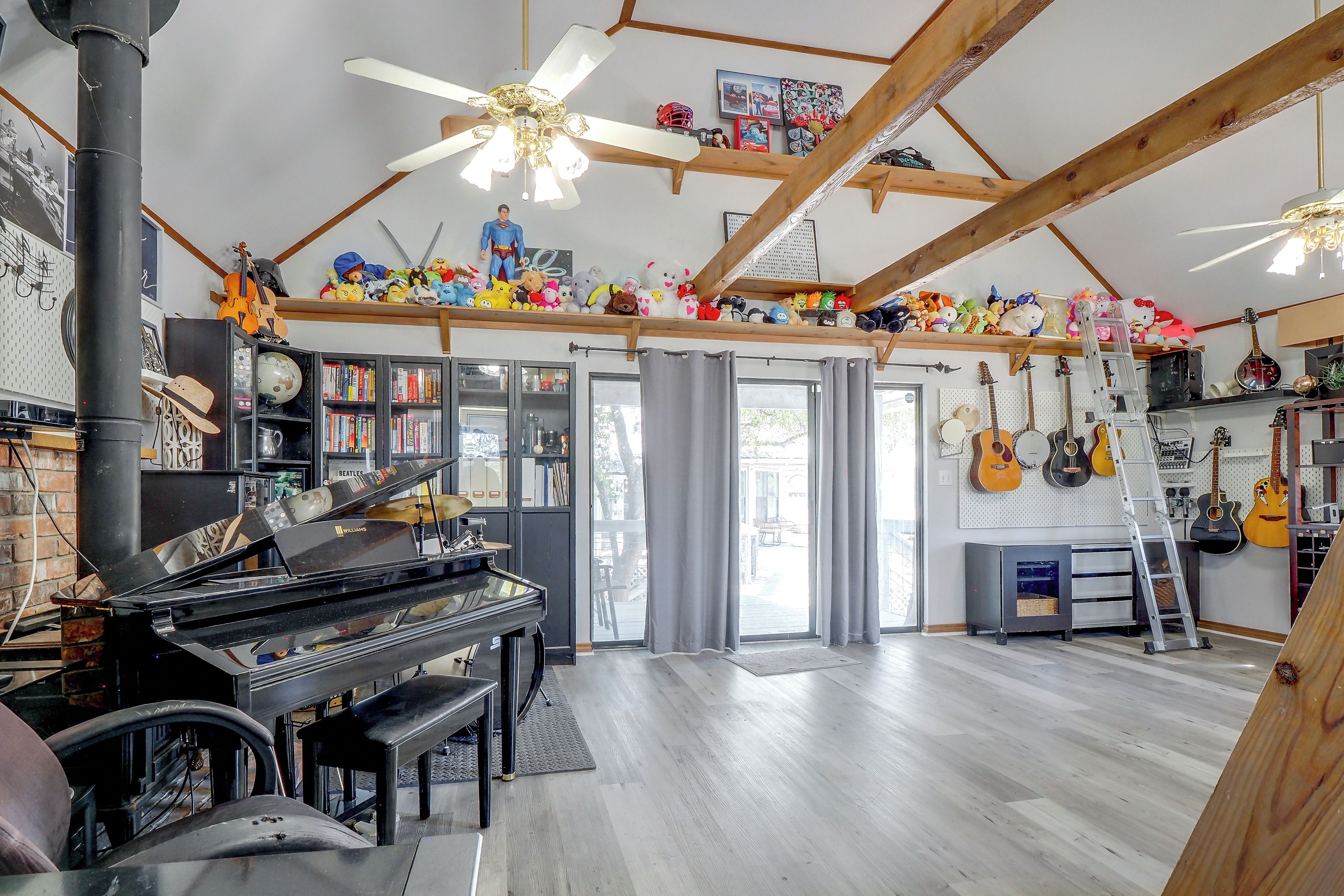 A spacious room with a grand piano, a ceiling fan, and a variety of musical instruments.