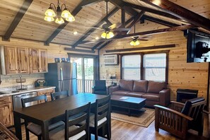A wooden cabin interior with a dining area, kitchen, and seating space. - RimRock Ranch Retreat Near Fort Robinson Trails (Crawford)