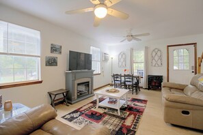 Una sala de estar con chimenea, sofás de cuero, televisor y ventilador de techo.