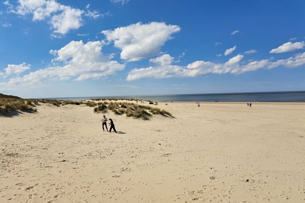 Une plage de sable avec des dunes et un ciel dégagé.