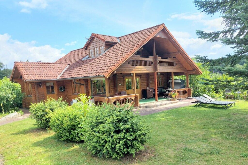 A wooden cabin with a sloped roof, a porch, and a small deck.