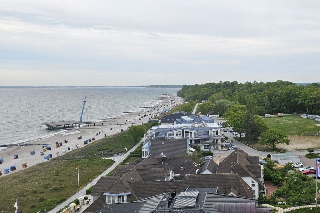 Een kustplaats met een strand, huizen en een pier.