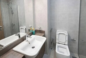 A bathroom with a double sink, a mirror, a toilet, and a shower. - Star by Azizi (Dubai)
