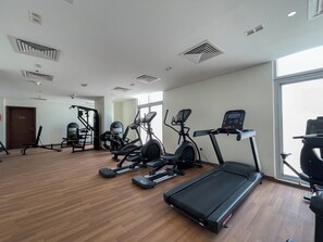 A gym with treadmills, elliptical machines, and weight equipment. - Star by Azizi (Dubai)