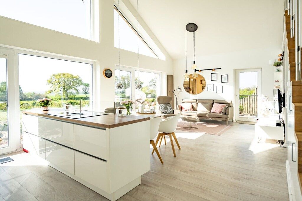 A spacious kitchen with a central island, large windows, and a view of the outdoors.